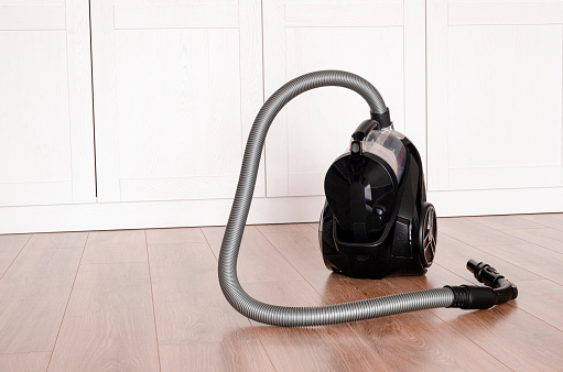 Black vacuum cleaner stands on the floor in the apartment. cleaning concept.