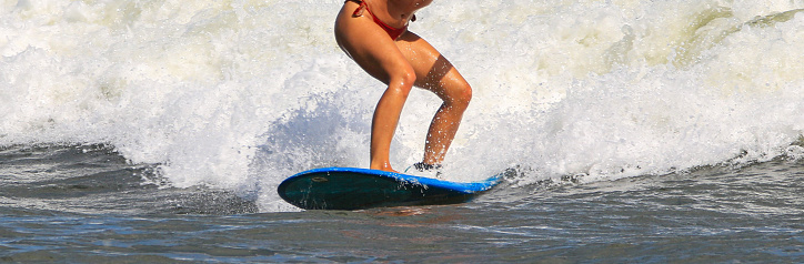 Beautiful Woman in a bikini Riding a Surfboard on an Ocean Wave