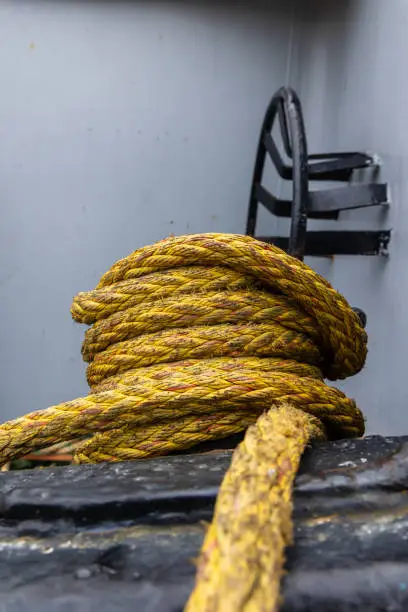 Photo of Mooring line wrapped around bitt-bollard with detail of ship in the background