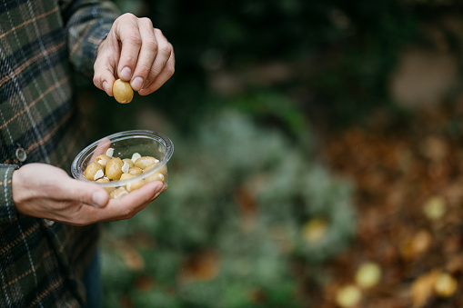 Man holding olives in a plastic container
