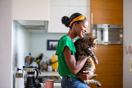 Smiling woman holding her cat at home