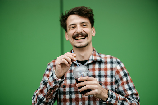 Man is holding a plastic cup with a drink