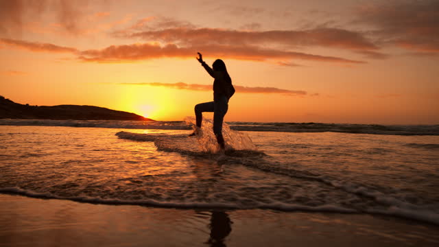 Girl child, silhouette and sunset by ocean, playing and splash feet with freedom, water and vacation. Kid, sea or beach with game in waves, running and summer sunshine at dusk on holiday in Mexico
