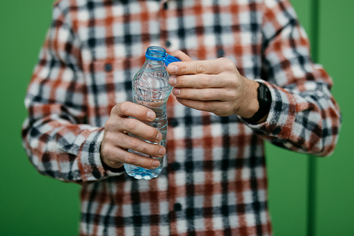 Man holds a plastic bottle of water outdoors