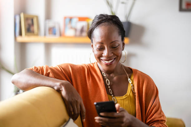 istock Mature woman using mobile phone while relaxing on a sofa at home 1840351873