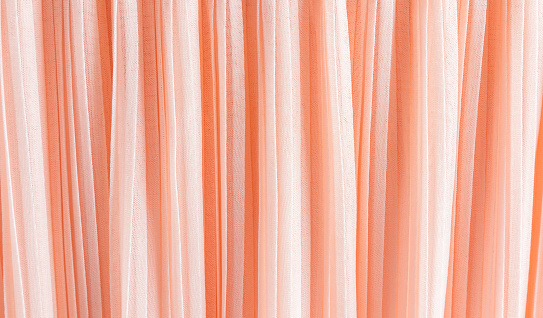 delicate chic textile background of peach color. pleats of chiffon or silk fabric. Abstract background for design. color trend 2024 Peach Fuzz