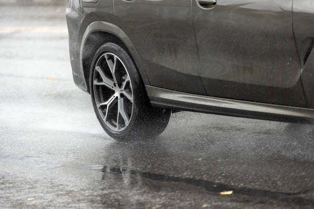 istock rain water splashing flows from wheels of grey car that moving fast on asphalt road 1840352421