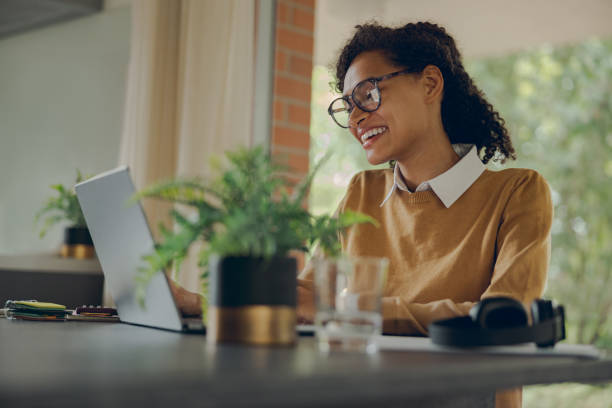 istock Smiling female manager working remotely on laptop from home while sitting near window 1840352476