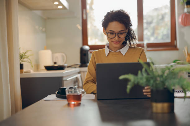 istock Smiling female manager working remotely on laptop from home while sitting near window 1840352605