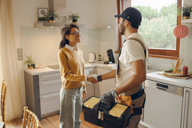 istock Professional repairman in uniform shaking hands with woman while standing at home kitchen 1840352884