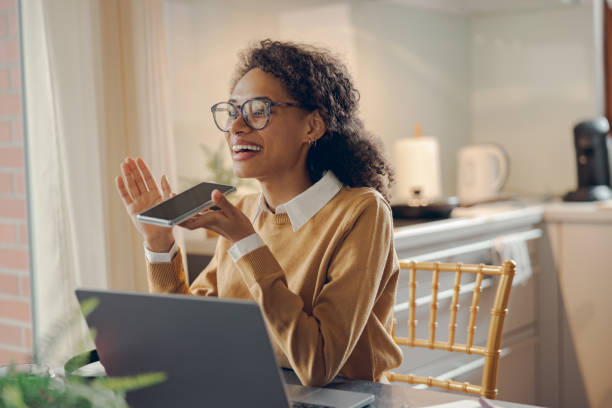 istock Female freelancer is record audio message on mobile phone while working on laptop from home 1840364109