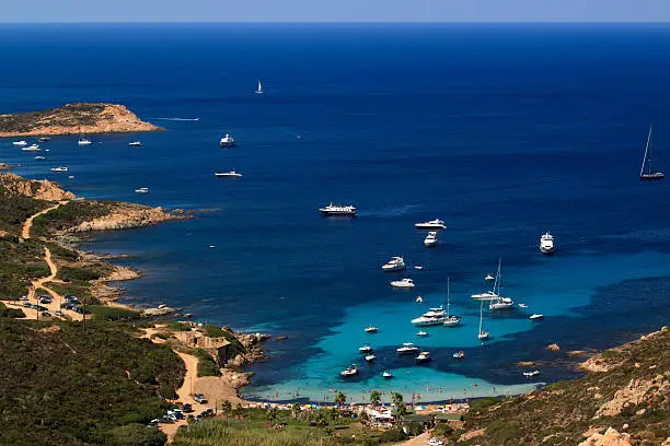 La Golfe de La Revellata just outside Calvi in Corsica. Boats and bathers relax in the calm, clear turquoise water of the Mediterranean Sea.