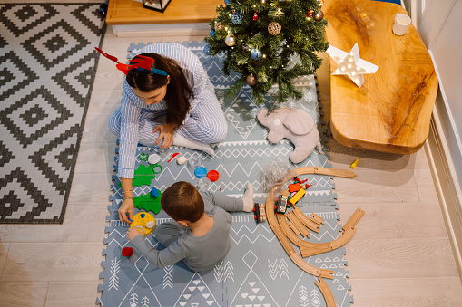 Photo of a young boy and his mother, decorating their living space for Christmas holidays