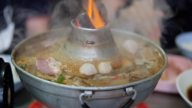 Thai style stainless steel hot pot with flame. Braised beef with offal and meatball soup in hot pot