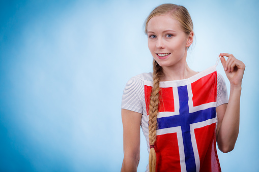 Blonde girl braid hair with norwegian flag, on blue. Scandinavian people.