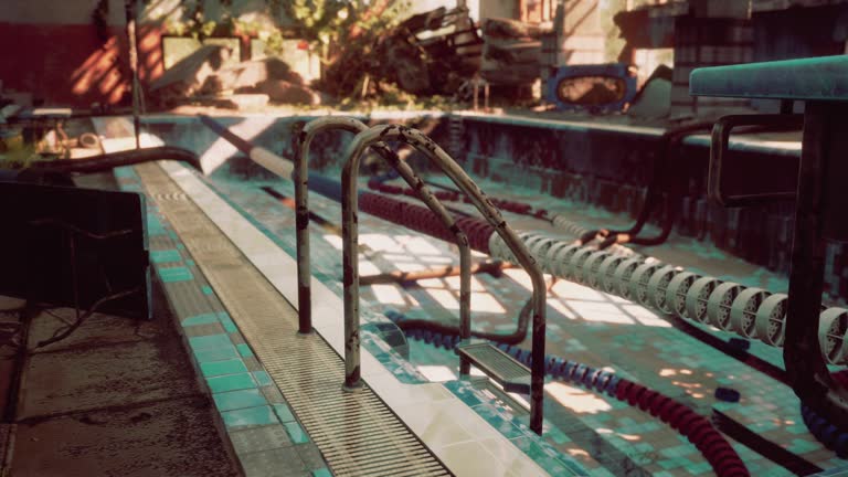 An abandoned swimming pool with a rusted metal railing