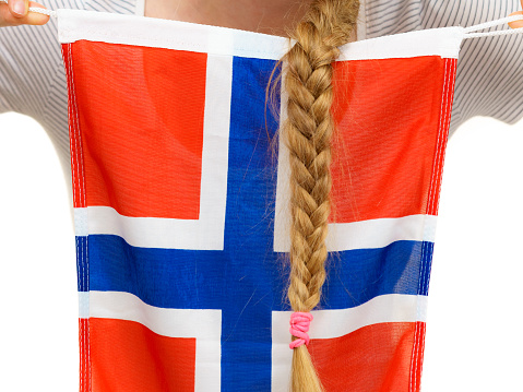 Blonde student girl unrecognizable young woman with long hair braid holding norwegian flag, close up. Education and travel.