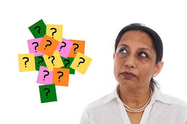 Close-up portrait of a thinking Indian businesswoman with question mark sign. Isolated on white background.