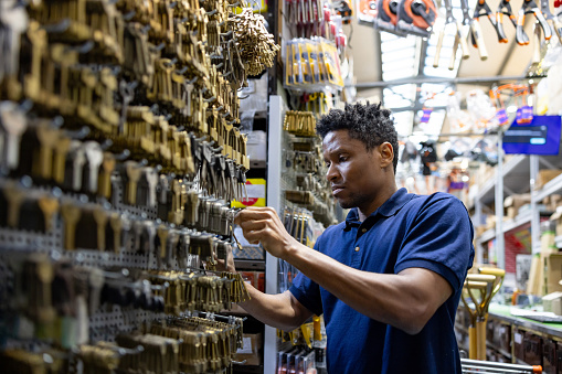 African American retail clerk searching for a key while working at a at a hardware store