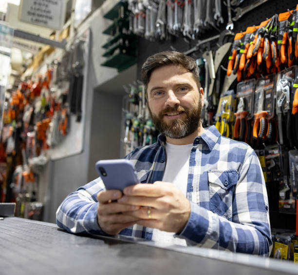 istock Man shopping at the hardware store and holding a reference on his mobile phone 1840468452