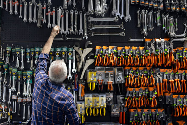 Rear view of a Latin American retail clerk grabbing a wrench at a hardware store