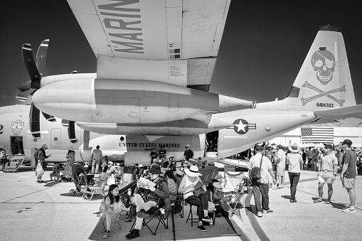 Miramar, California, USA - September 23, 2023: Airshow fans get relief from the sun under the wing of a C-130 Hercules at America's Airshow 2023.