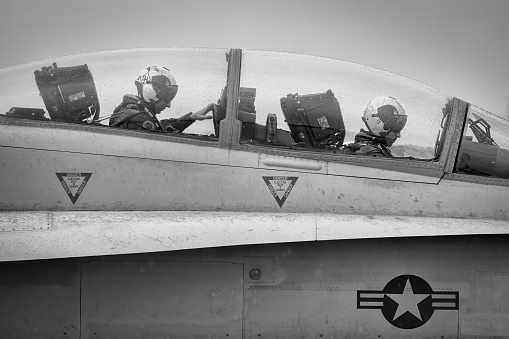 Miramar, California, USA - September 22, 2023: Two naval aviators sit in the cockpit of an F-18 Hornet, while it rains, at America's Airshow 2023.