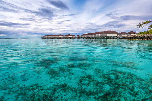 Scenic view of water villas in Maldives after sunset with turquoise pristine water and dramatic sky