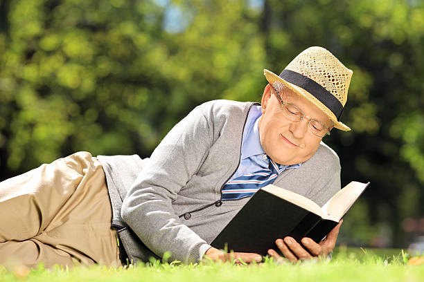 istock Senior man lying on grass and reading book 184049532