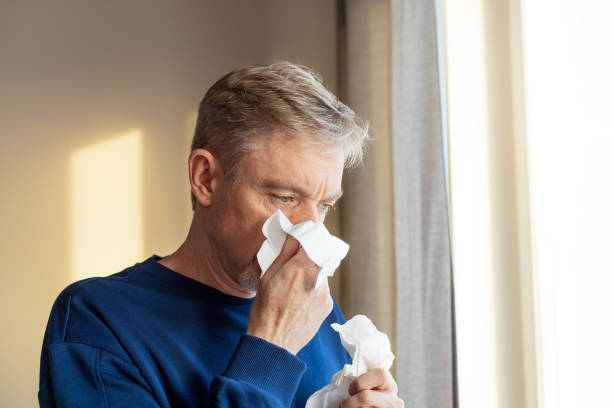 A 50 year old man with a cold uses a handkerchief stock photo