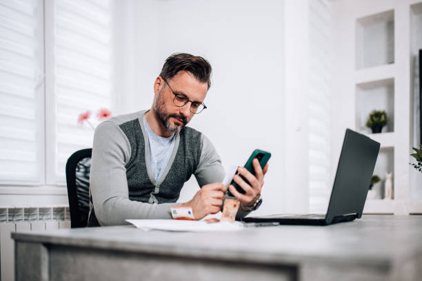 istock Mid adult man stays organized with mobile bill pay 1840503731