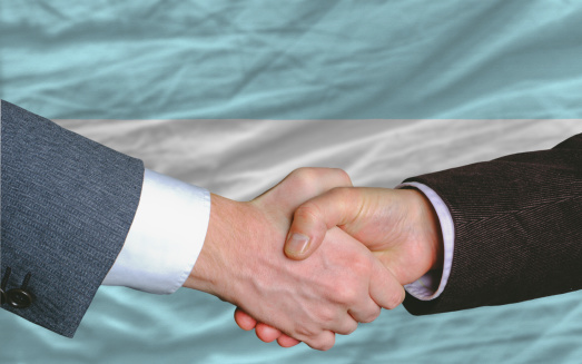 two businessmen shaking hands after good business investment  agreement in argentina, in front of flag
