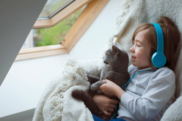 istock Happy little boy listening music while playing with a cat 1840557199