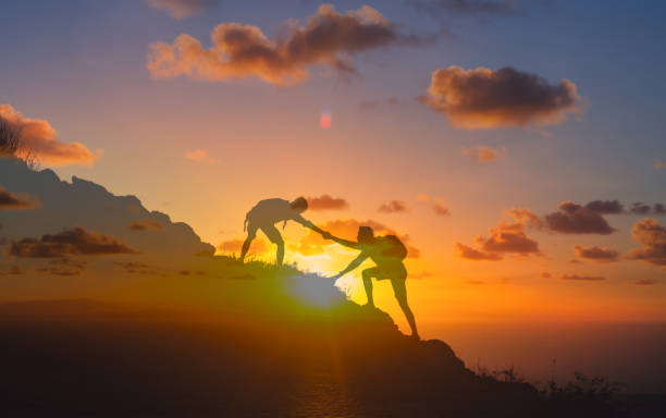 Hikers helping each other climb the mountain. Helping hands.