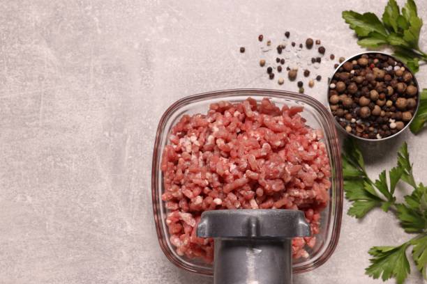 istock Manual meat grinder with beef mince, peppercorns and parsley on light grey table, flat lay. Space for text 1840562058