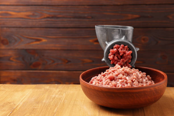 istock Manual meat grinder with beef mince on wooden table, space for text 1840564747