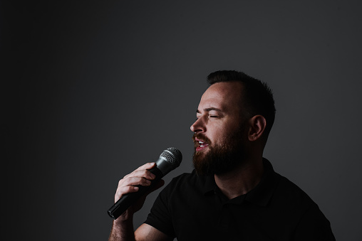 Close up male hand holding High quality dynamic microphone and singing song or speaking talking with people on isolated white background. Male testing microphone voice for interview