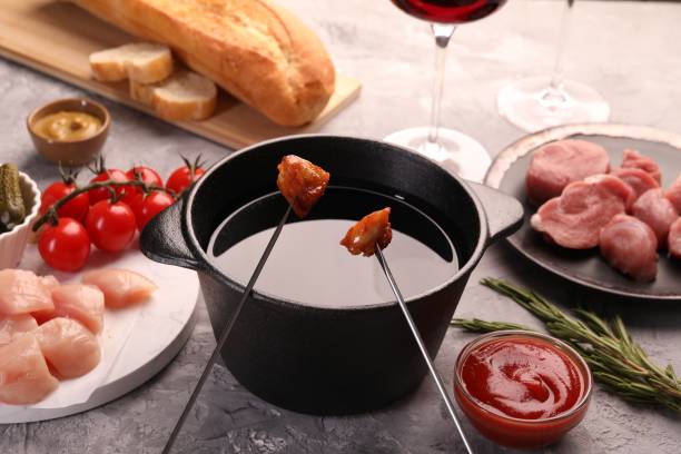 istock Fondue pot, forks with fried meat pieces and other products on grey textured table 1840577627