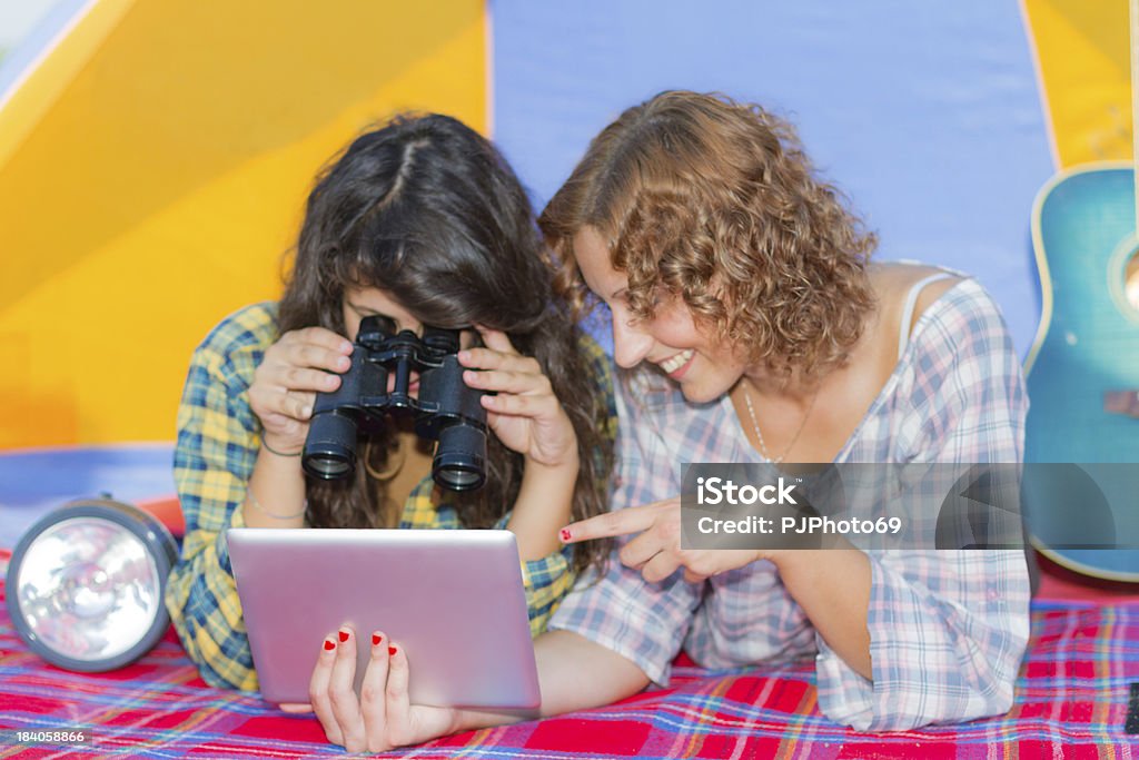 Deux jeunes femmes faire du camping de la rivière lecture sur Tablette numérique - Photo de Activité de loisirs libre de droits