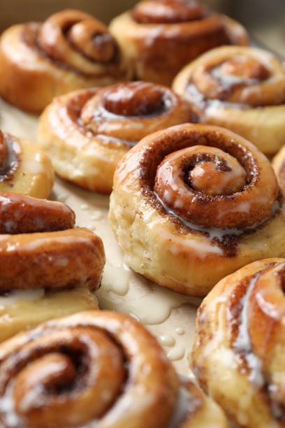 istock Tasty cinnamon rolls with cream on parchment paper, closeup 1840594481