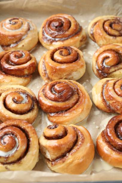 istock Tasty cinnamon rolls with cream on parchment paper 1840598154