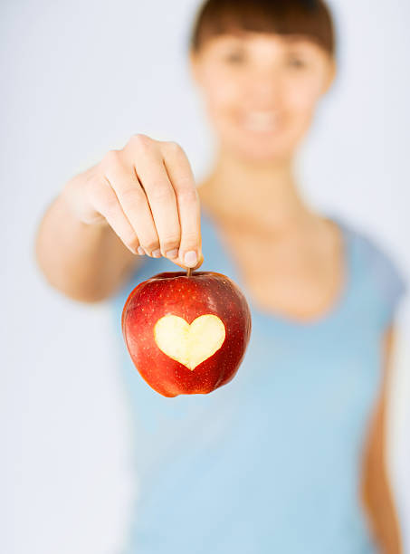 istock woman hand holding red apple with heart shape 184061110