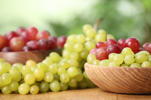 Different fresh ripe grapes on wooden table, closeup
