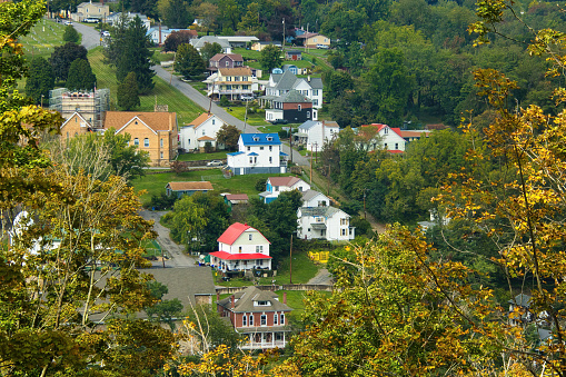 Landscape on an early Autumn day featuring the hilltop view of a quaint, small town viewed below the Great Allegheny Passage recreational trail in Pennsylvania.