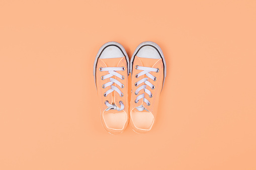 Sneakers top view on peach fuzz color background, color of the year 2024
