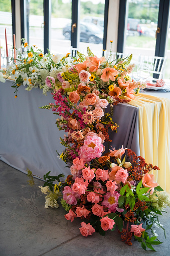 Amazing composition of various colorful flowers made on wedding table for newlyweds. Concept of event and celebration.