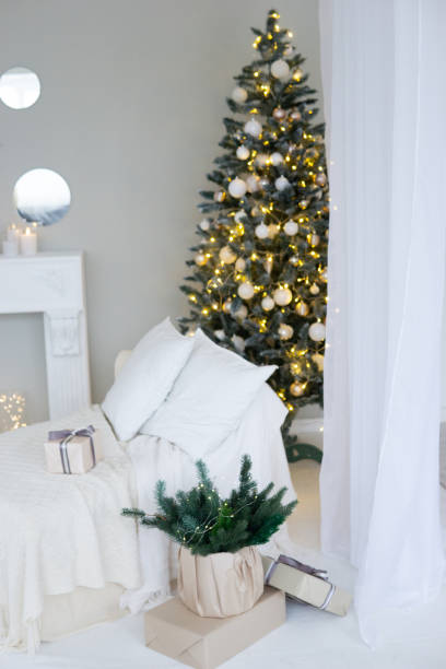 istock Bright interior with a false fireplace decorated for Christmas. Christmas trees with garlands, balloons and lights. 1840646923