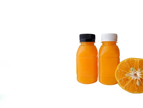 The white background in the picture is that there are two bottles of orange juice freshly squeezed from fresh oranges. There are two bottles, a black cap and a white cap, full of orange juice, and close to each other there are halved orange