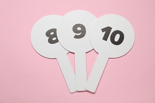 Auction paddles with numbers on pink background, top view