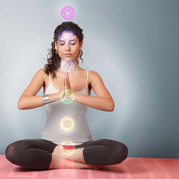 Beautiful young woman doing yoga exercise Beautiful young woman doing yoga meditation in lotus position with activated chakras over body chakra photos stock pictures, royalty-free photos & images